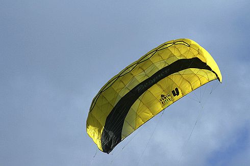 A four-line yellow and black parafoil kite in flight.